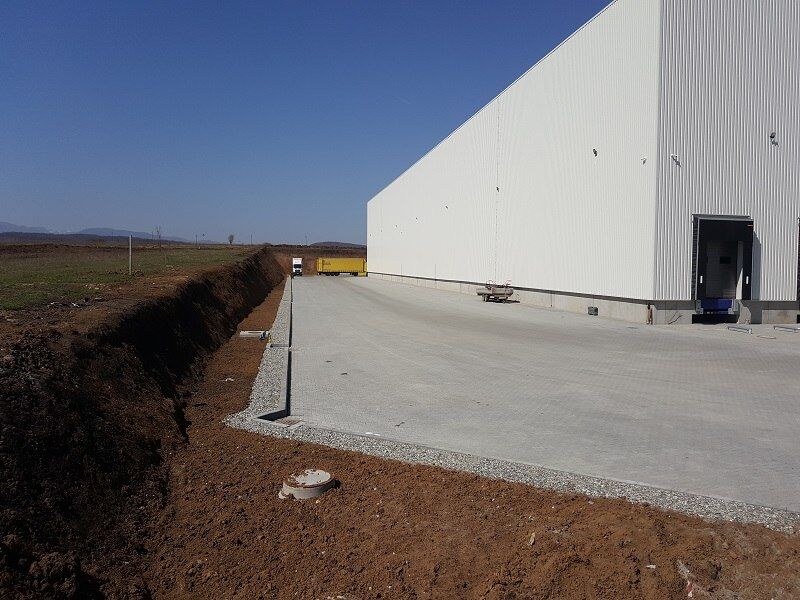 Hala centrului logistic KHD din Sibiu, cu fațada din panouri albe, ușa de încărcare pentru camioane și platforma exterioară de-a lungul fațadei