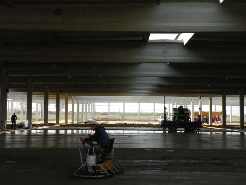 Finisarea mecanică a unei pardoseli industriale, cu elicopterul, într-o hală cu structură prefabricată