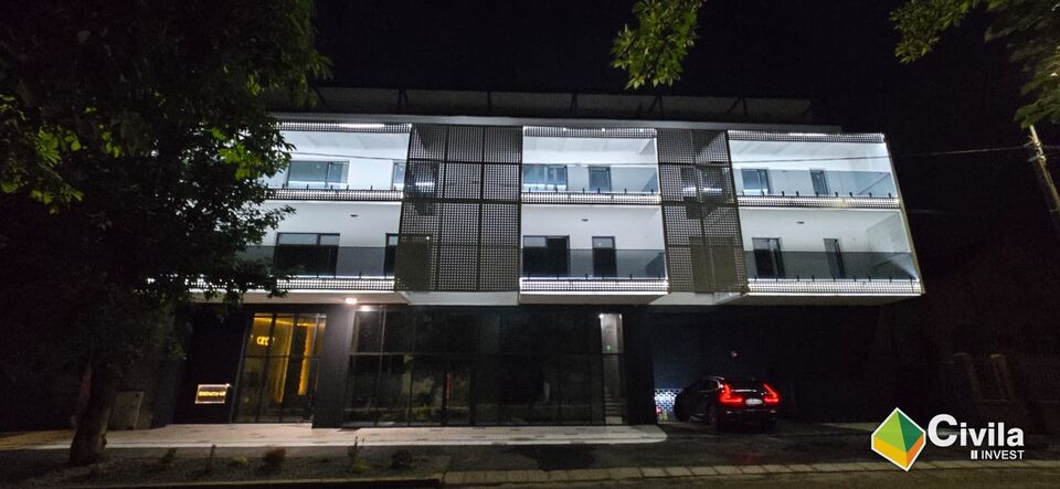 Blocul de locuințe colective și aparthotel din zona Nymphaea, Oradea, fotografiat seara, cu fațada iluminată