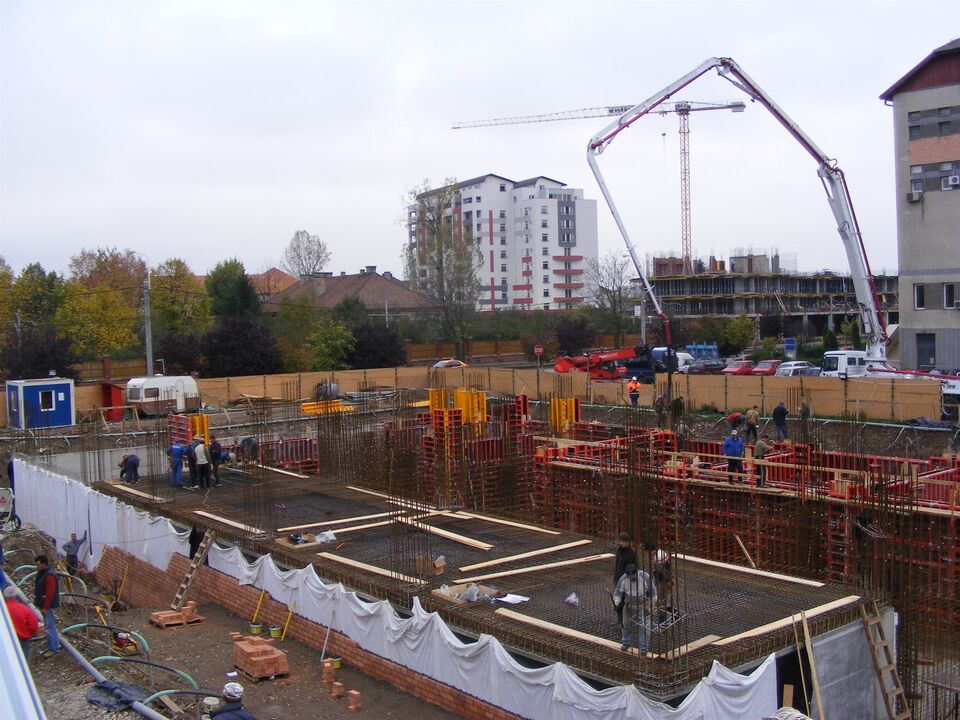 Șantierul Hotelului Ramada din Oradea, în groapa de fundație: armături, cofraje metalice pentru pereții infrastructurii și pompa de beton la lucru, cu macaraua turn în fundal
