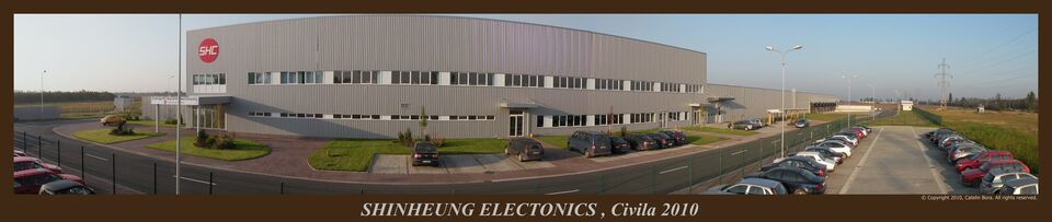 Panorama fabricii ShinHeung Electronics din Oradea, finalizată în 2010: fațada cu sigla SHC, aleea de acces, spațiile verzi și parcările