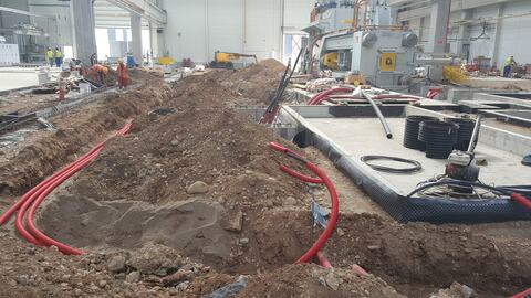 Tuburi pentru cabluri pozate în șanțuri, lângă o fundație din beton, în hala Alu-Menziken