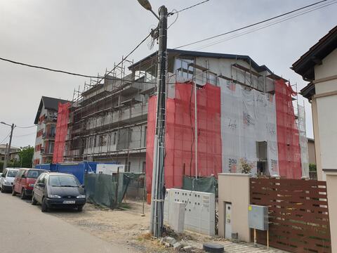 Blocul P+3 văzut din stradă, cu schelele și plasa de protecție pe fațade