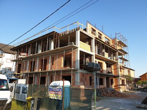 Structura blocului P+3 ridicată până sus, cu zidăria etajelor, schela de pe colț și parapetul de protecție de pe ultima placă
