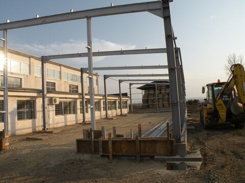 Steel frames erected next to the existing building, with foundation formwork in progress, at the ETS România factory in Biharia