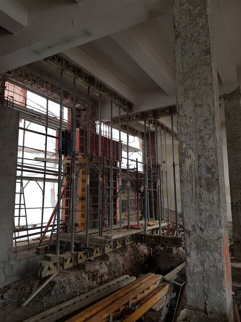 Stâlp din beton și cofraje sprijinite pe popi lângă ferestrele parterului, la clădirea Faber
