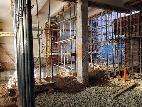 Stâlp din beton, strat de pietriș pe jos și cofraje sprijinite pe popi lângă pereți