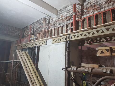 Cofraje și grinzi de cofraj montate pe un perete nou din beton, sub planșeul existent al clădirii Faber
