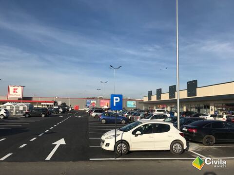 Parcarea centrului comercial din Făgăraș, cu locurile și săgețile marcate; în dreapta, clădirea cu magazine, iar în fundal un hipermarket vecin