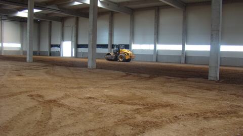 Cilindrul compactor pe umplutura din interiorul unei hale închise, înainte de pardoseală