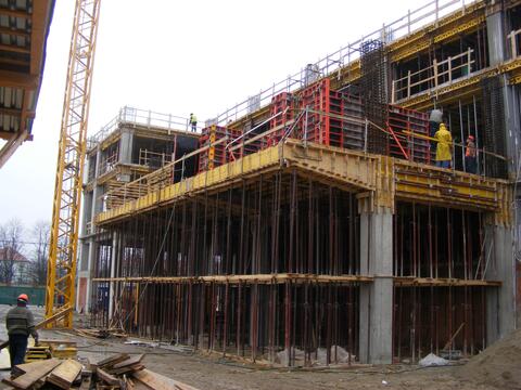Clădire cu structură din beton armat în execuție, cu planșeul cofrat pe popi și macaraua-turn alături