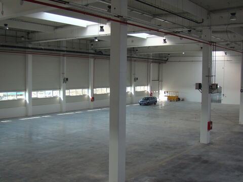 Hală finalizată, cu stâlpi albi, pardoseala industrială gata și o mașină parcată în interior