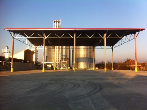 Platforma betonată și copertina metalică de la baza de colectare cereale Ardealul SA din Salonta, cu silozurile în fundal