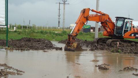 Excavator săpând într-un teren cu apă băltită