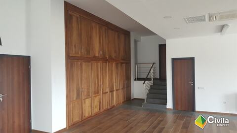 Încăpere cu un perete întreg de dulapuri din lemn, uși din lemn și scara cu balustradă din inox