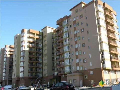 Blocurile din Cartierul Prima cu fațadele finisate în bej și maro, văzute din parcarea din fața lor