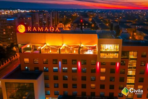 Ultimul nivel al Hotelului Ramada Oradea seara, cu terasa iluminată și sigla Ramada