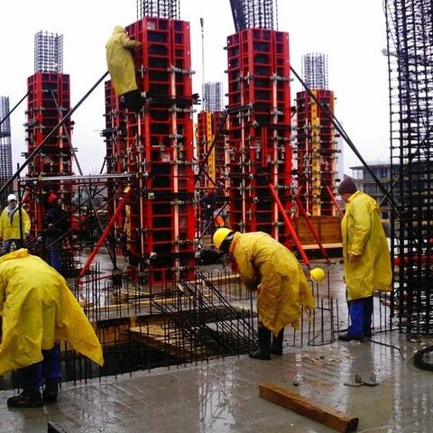 Echipa de pe șantier, în pelerine, la cofrajele metalice ale stâlpilor Hotelului Ramada, pe ploaie