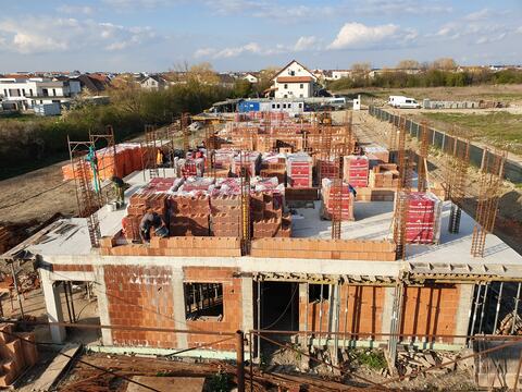 Zidăria etajului în lucru pe planșeul turnat, cu paleții de cărămidă pe placă, la Royal Valley