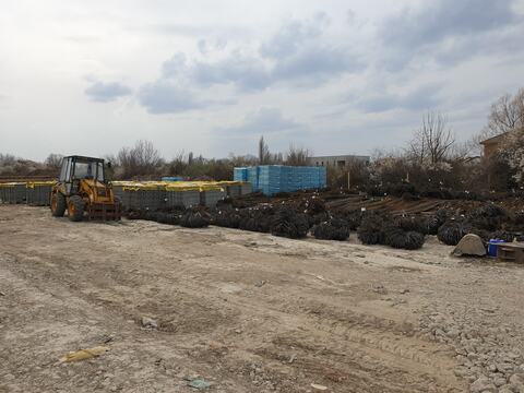 Oțel-beton și paleți cu materiale pe platforma șantierului Royal Valley, cu buldoexcavatorul alături