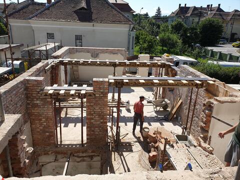 Casa veche văzută de sus, fără etaj: ziduri de cărămidă cu goluri noi, sprijinite pe grinzi de cofraj și popi metalici