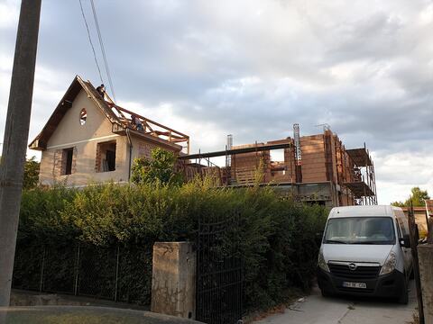 Casa veche cu acoperișul în desfacere și, alături, corpul nou din blocuri ceramice, cu schelă și mustăți de armătură