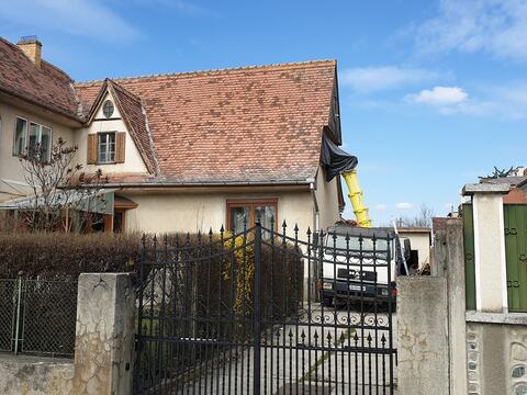 Casa veche din Sibiu la începutul lucrărilor, cu tubul galben pentru moloz coborât de la acoperiș spre un camion din curte