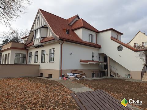 Fațada laterală a locuinței S+P+M din Sibiu după reabilitare, cu scara exterioară, fereastra rotundă și acoperișul din țiglă
