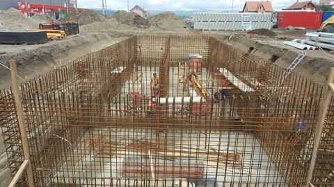 Armătura pereților din beton armat, ridicată în săpătură, cu muncitori la lucru înăuntru