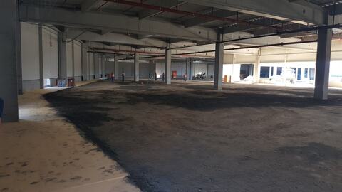 Interiorul clădirii închise, cu stâlpii prefabricați, conductele roșii sub acoperiș și umplutura nivelată; în fund, un aparat de măsură pe trepied